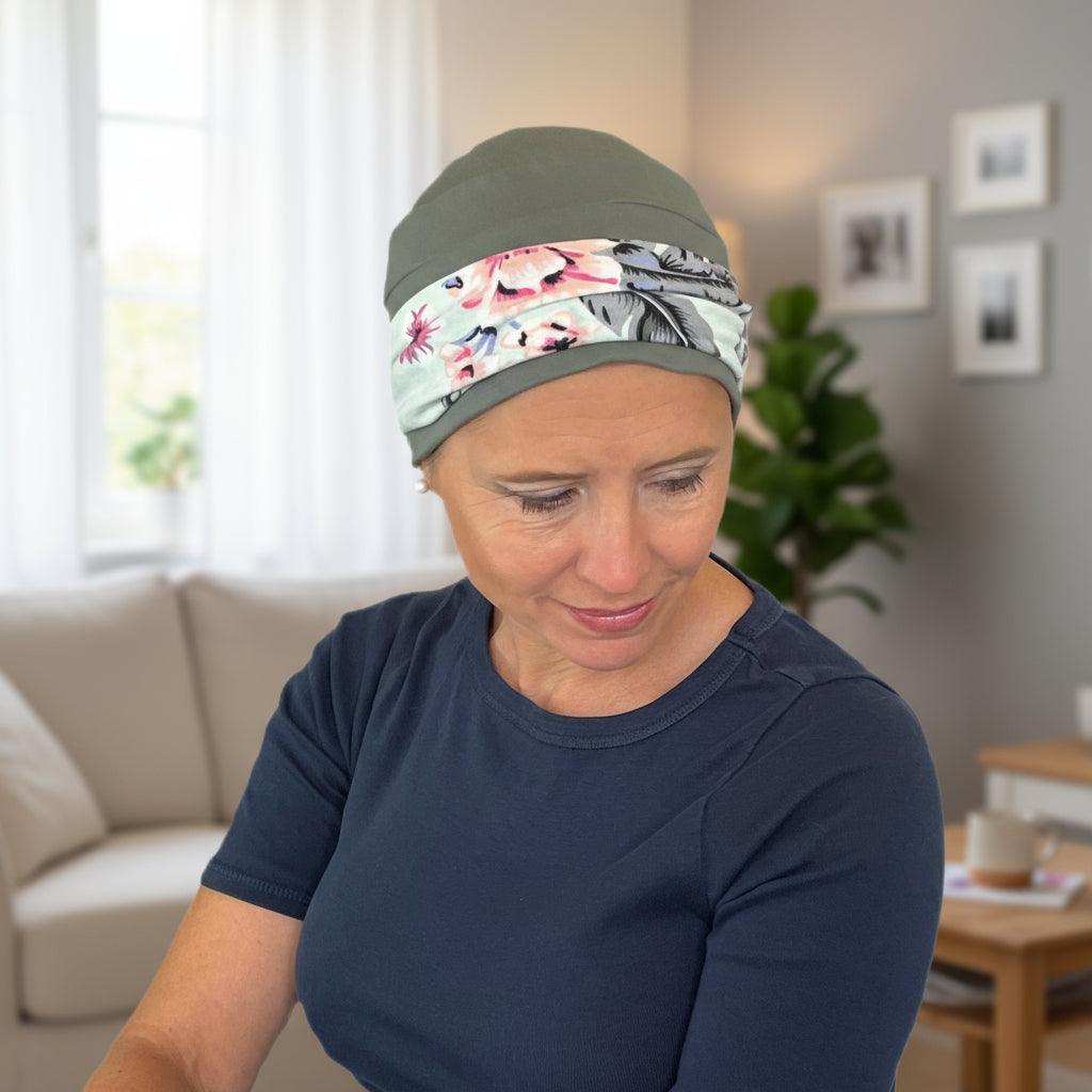 Woman wearing a hat for cancer patients with a floral pattern in a living room setting