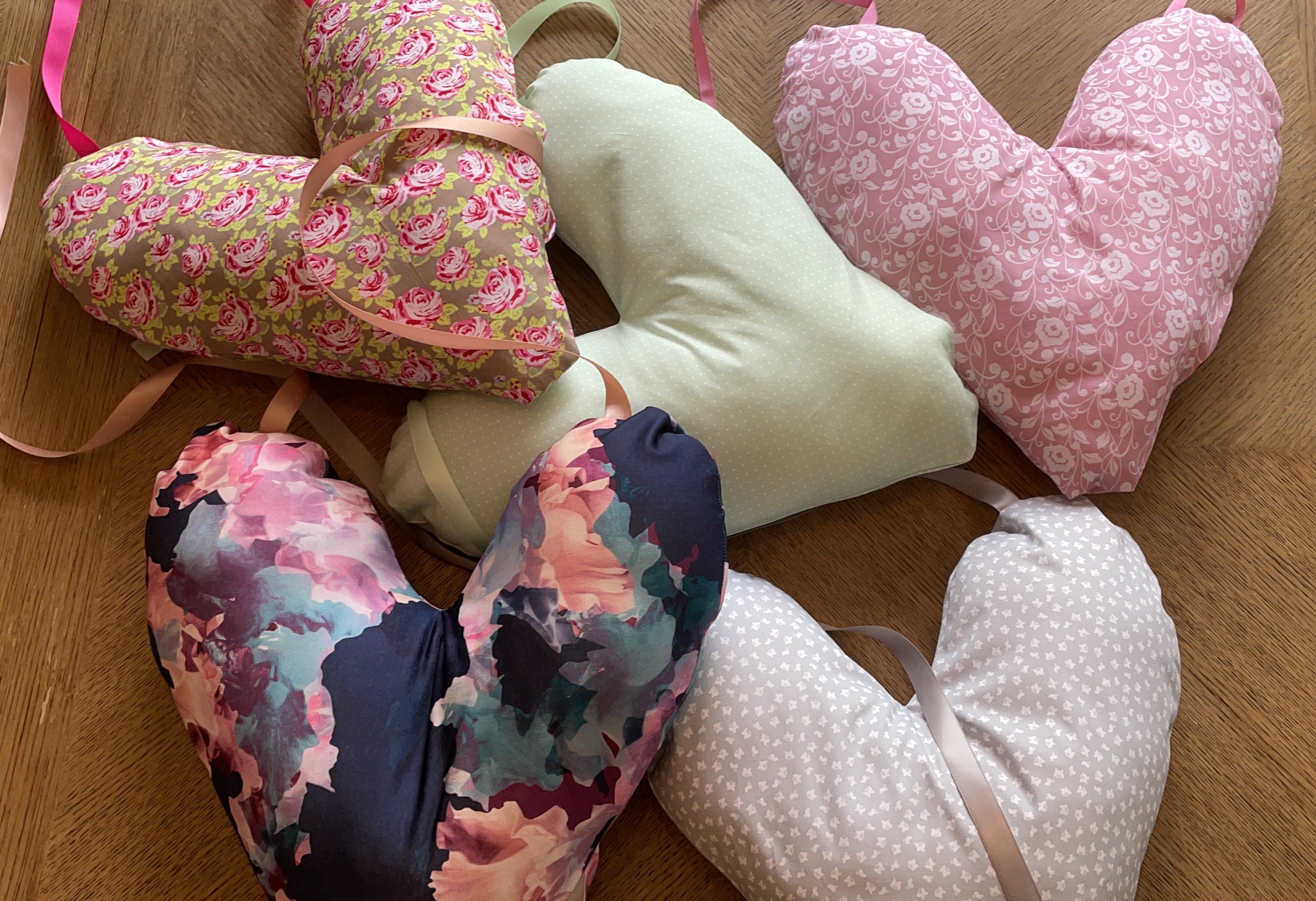 Heart-shaped cushions with floral patterns on a wooden surface