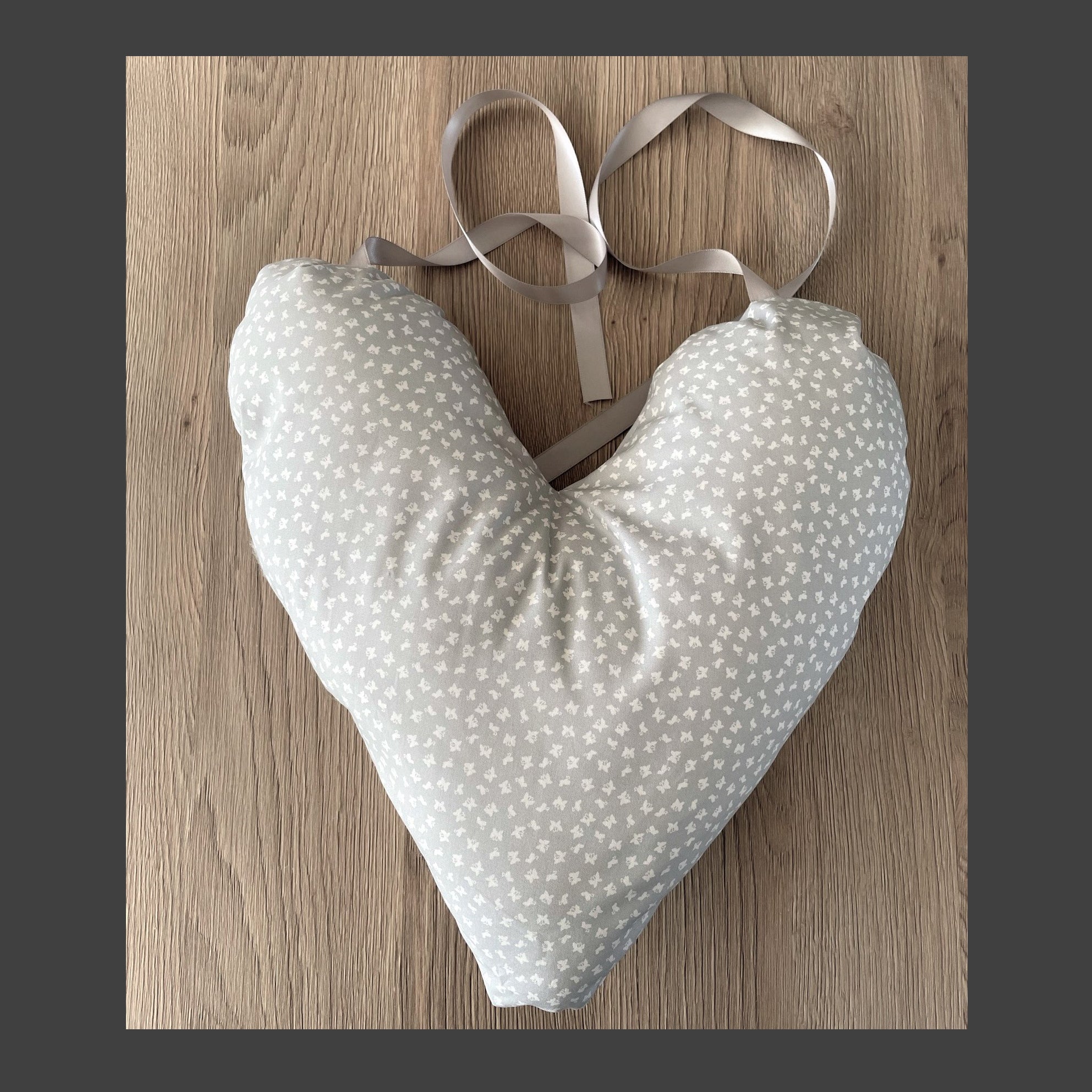 Heart-shaped mastectomy pillow with white polka dots and ribbons on a wooden surface
