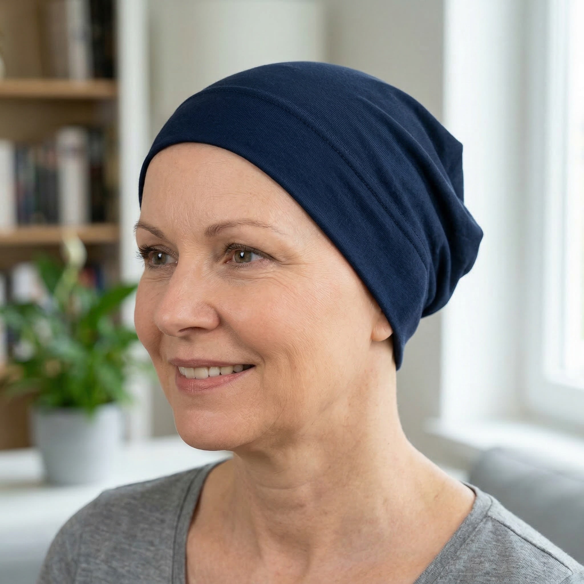 Woman wearing a navy cancer sleep hat in a home setting