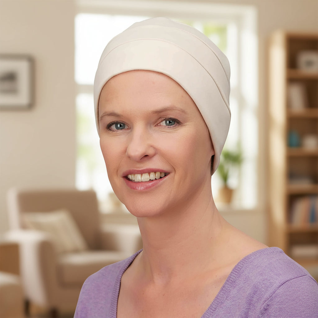 Woman wearing a white chemo sleep hat in a home setting