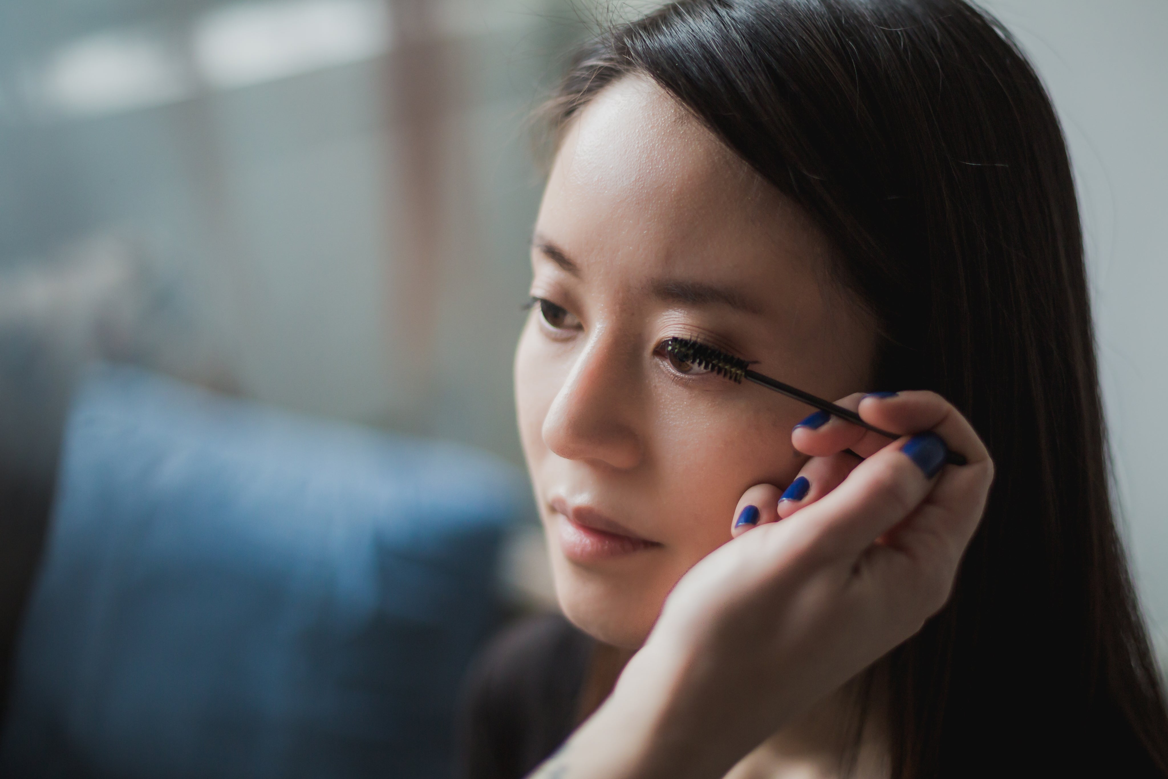 A woman putting on mascara