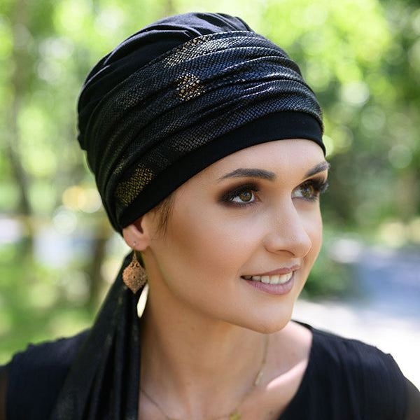 Woman wearing a black chemo headscarf with gold patterns outdoors