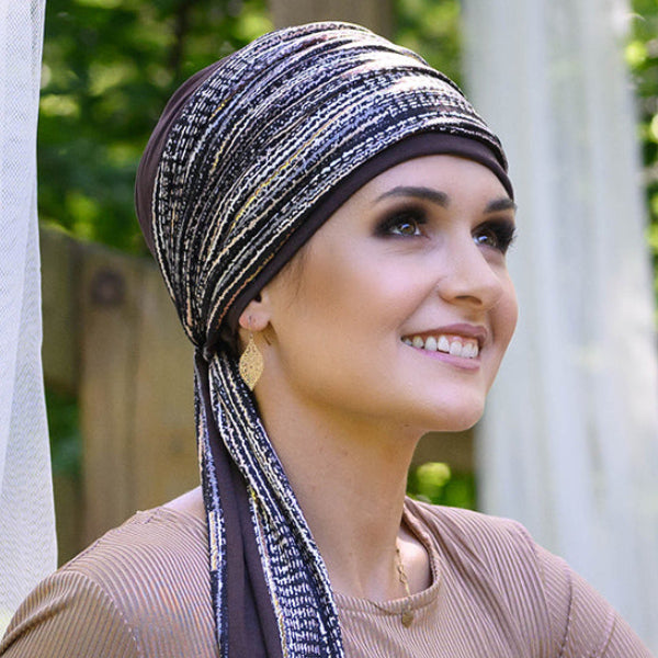 Woman wearing a patterned cancer headscarf outdoors with greenery in the background
