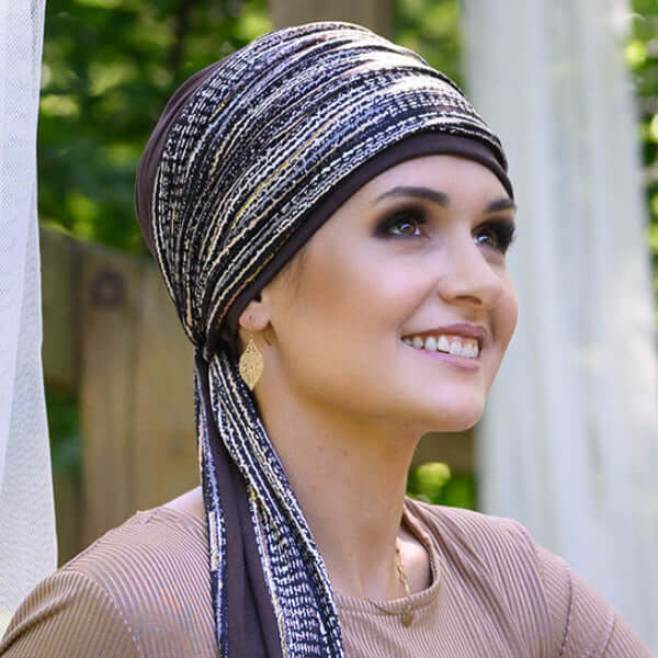 Woman wearing a patterned cancer headscarf outdoors with greenery in the background
