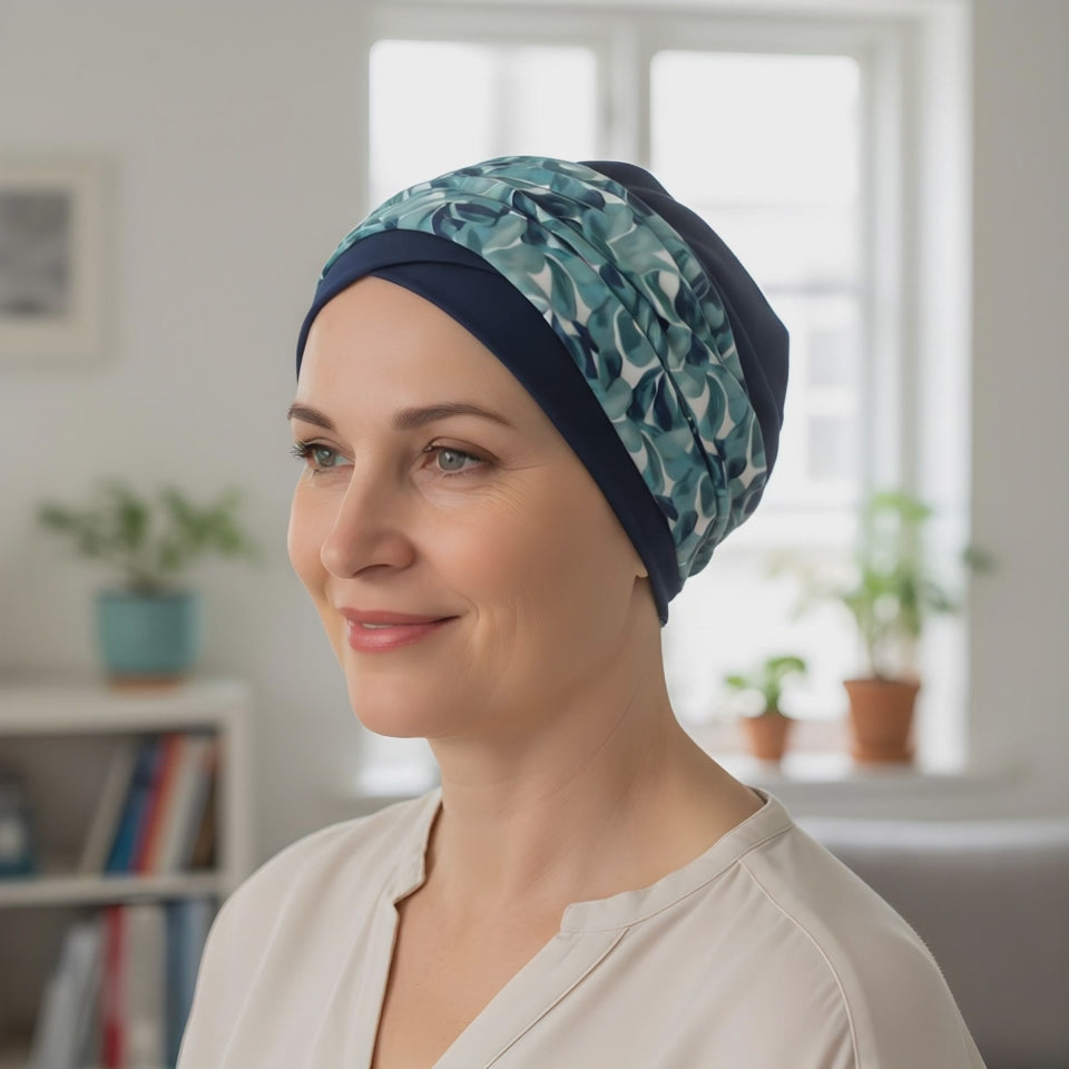 A woman wearing a chemo hat and headband teal and blue looking at the camera and smiling