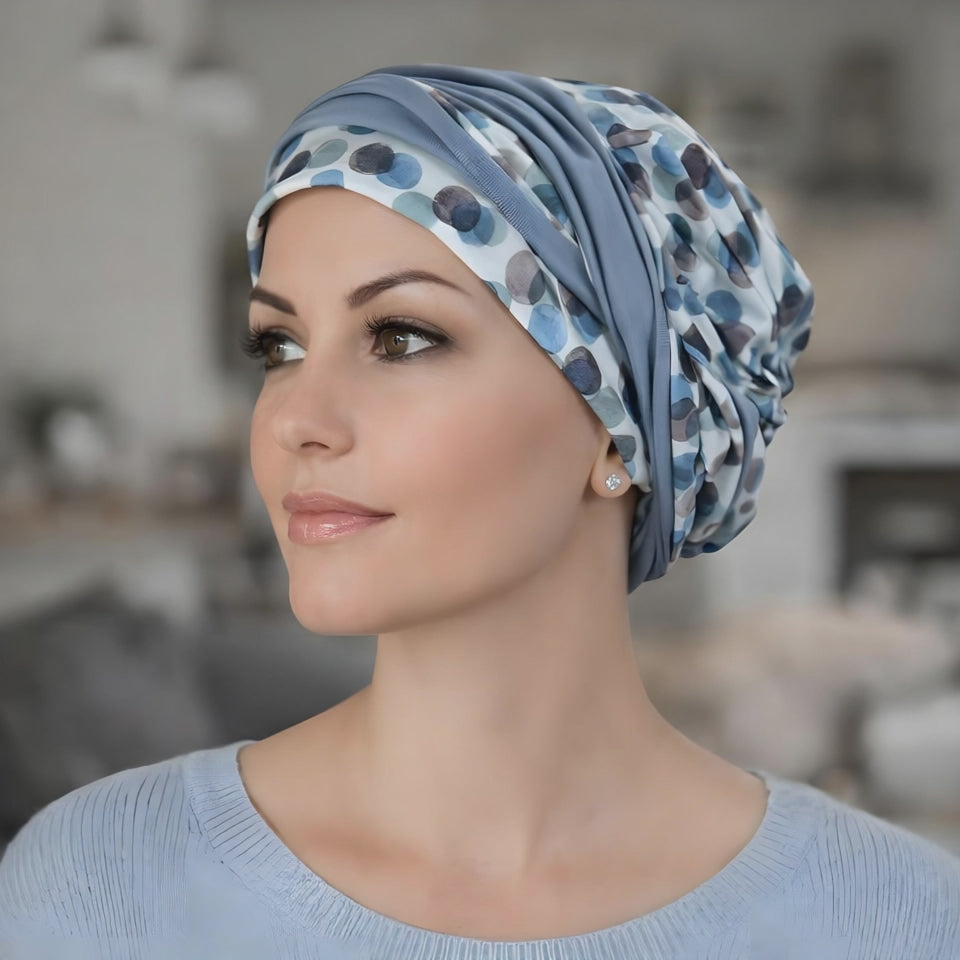 A woman wearing a chemo headscarf in blue looking at the camera and smiling
